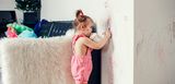 Kreativer Nachwuchs trifft weiße Wand – zum Glück haftpflichtversichert Kleinkind kritzelt mit Filzstift an eine weiße Wand im Wohnzimmer