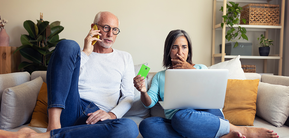 Phishing? Fake-Shop? Zum Glück gibt es die Cyberversicherung. Älteres Paar auf dem Sofa mit Laptop und Karte – beide wirken besorgt. Mögliche Darstellung von Online-Betrug oder Phishing.